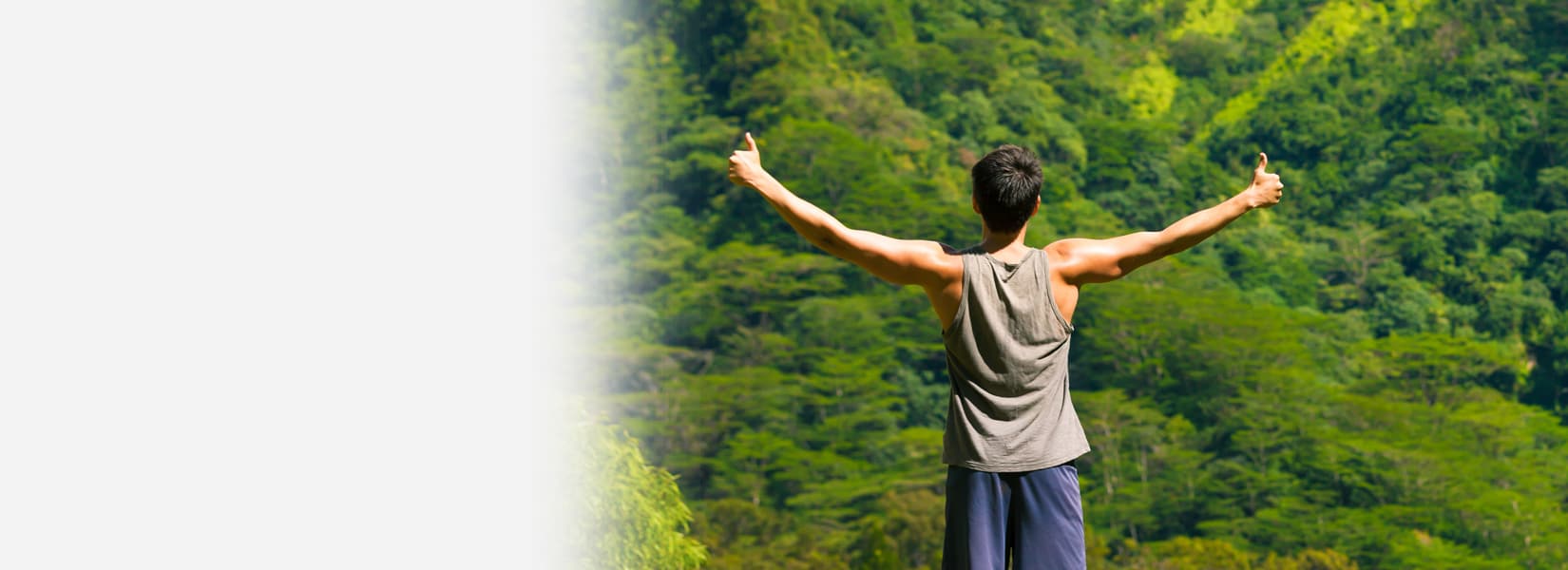 man with arms outstretched in green wilderness